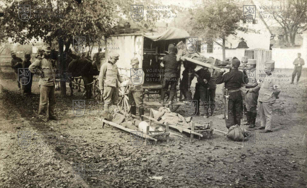 Příslušníci zdravotní služby zeměbraneckého pěšího pluku č. 8 nakládají do vozu vojáky zraněné na srbské frontě, 1914